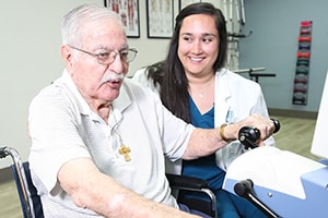 A physical therapist helping an elderly man at Hanford do therapy