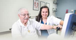 A physical therapist helping an elderly man at Hanford do therapy
