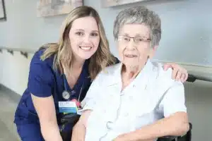 A caregiver and an elderly woman in a wheelchair at Hanford Post Acute