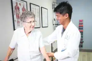 A therapist and an elderly woman in the rehab gym at Hanford Post Acute