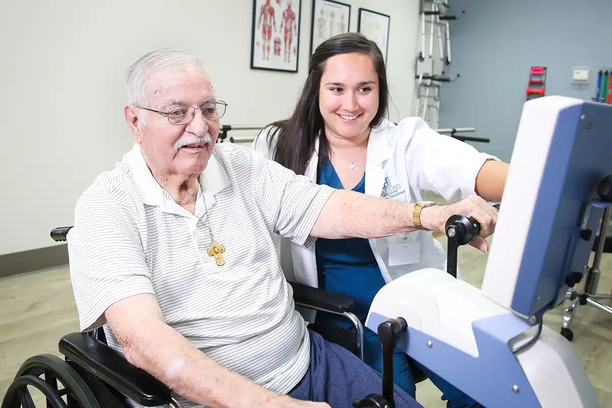 A therapist and an elderly woman in the rehab gym at Hanford Post Acute